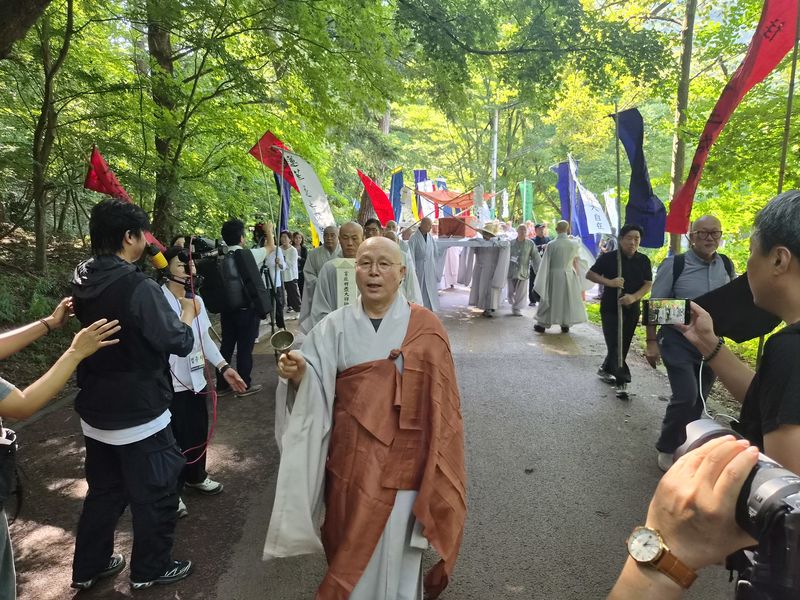 만장기를 든 사부대중들의 행렬과 고 명진 스님의 법구가 25일 법주사 다비장으로 이운되고 있다. 2026.8.25 ⓒ 뉴스1 임양규 기자