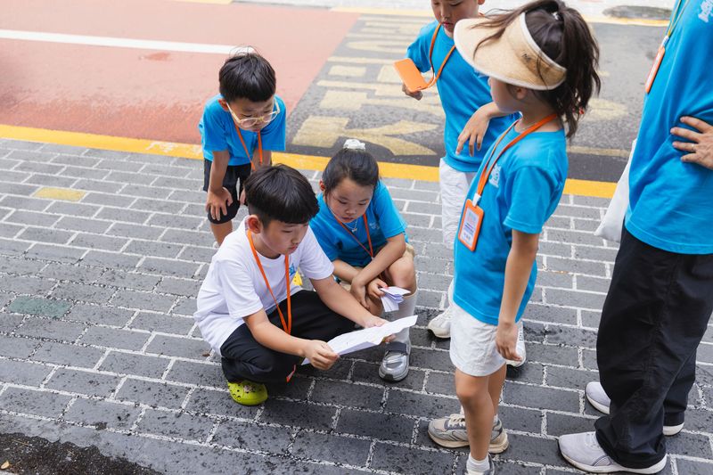 22일 ‘2026 만만한 원도심-여름캠프’에 참여한 어린이들이 제주시 원도심에서 활동지를 살펴보며 탐험을 이어가고 있다. 어린이들은 산지천과 동문시장, 관덕정, 칠성로 등을 직접 걸으며 도시의 공간과 이야기를 찾아 나섰다. /사진=제주특별자치도 소통협력센터 제공