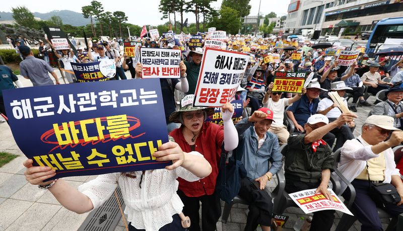 육·해·공 사관학교 통합형인 '국군사관학교' 창설 관련 공청회가 열린 26일 오후 서울 용산구 전쟁기념관 앞에서 열린 육·해·공 사관학교 통폐합 반대 집회에서 참석자들이 사관학교 통폐합에 반대하는 손팻말을 들고 구호를 외치고 있다. 뉴스1