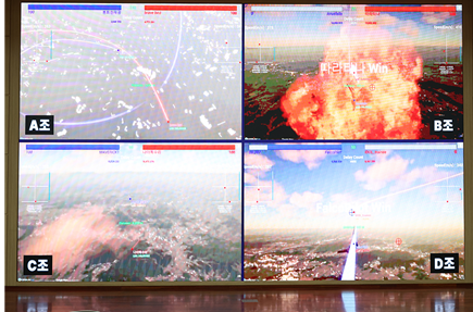 27일 한국항공대학교에서 열린 '제1회 한국항공대학교 총장배 2026 AI Pilot Top Gun Challenge' 예선에서 대회 진행 스태프들이 경기를 운영하고 있다. 대회장 화면에 중계된 AI 공중전 경기 장면. 예선 참가팀의 F-16 전투기들이 서울 상공을 비행하며 교전을 펼치고 있다. 한국항공대 제공