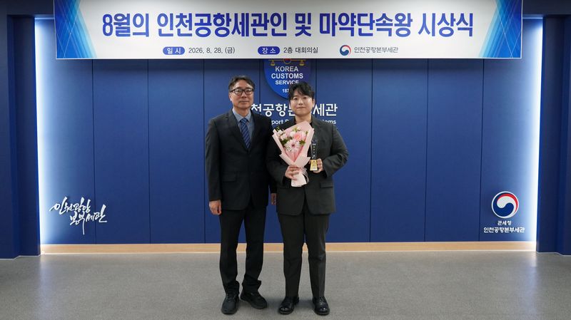 김정 인천공항본부세관장(왼쪽)이 28일 '8월의 인천공항 세관인'으로 선정된 김준경 주무관에게 상패를 전달하고 기념촬영을 하고 있다. 인천공항본부세관 제공