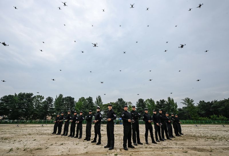 드론ㆍ로봇 전술시범단 장병들이 군집비행 중인 드론을 배경으로 기념사진을 촬영하고 있다. 육군 제공