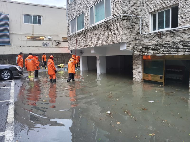 30일 울산 동구 방어동 일대에 시간당 100mm에 육박하는 집중호우로 주택과 도로가 침수되는 피해가 발생했다. 한 빌라 주차장과 출입구가 침수돼 출동한 소방대원들이 배수 지원과 안전 조치를 취하고 있다. 울산소방본부 제공