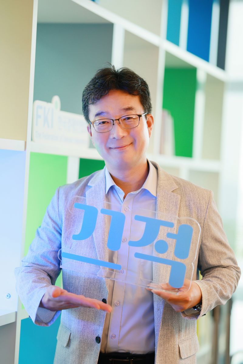 한국경제인협회 김용춘 홍보실장이 30일 서울 영등포구 FKI 타워에서 진행한 인터뷰에서 한경협 SNS 채널인 '끄적' 문구를 들고 포즈를 취하고 있. 한경협 제공
