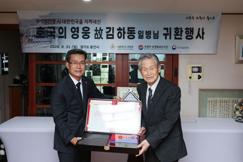전병희 국방부 유해발굴감식단장(왼쪽)이 31일 유가족 대표인 고 김하동 일병의 남동생 김하준씨에게 호국의 얼 함을 전달하고 있다. 국방부 제공