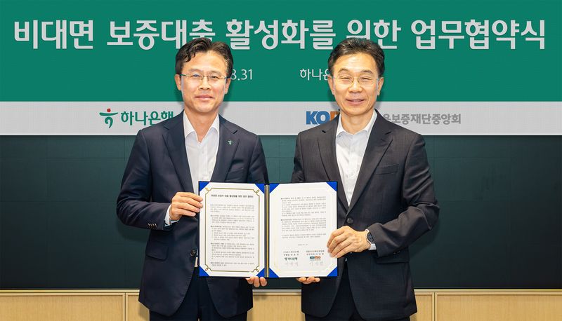 하나은행은 31일 오후 하나은행 을지로 본점에서 '비대면 보증부 대출 활성화를 위한 업무협약'을 체결했다. 이날 협약식에 참석한 서유석 하나은행 기업그룹 부행장(사진 왼쪽)이 이상천 신용보증재단중앙회 전무이사(사진 오른쪽)와 함께 협약서를 들고 기념촬영을 하고 있다. 2026.08.31 / 사진제공=하나은행