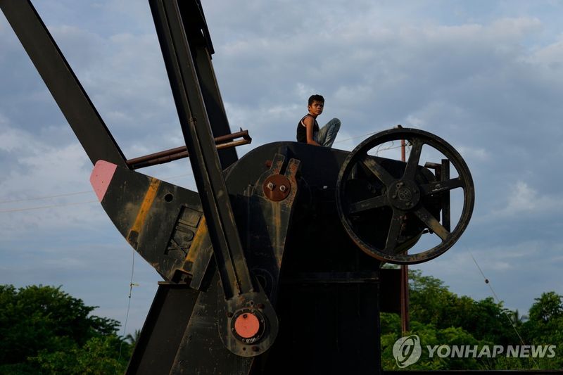 베네수엘라의 가동을 멈춘 원유 채굴기 위에 한 소년이 올라가 있다. 연합뉴스