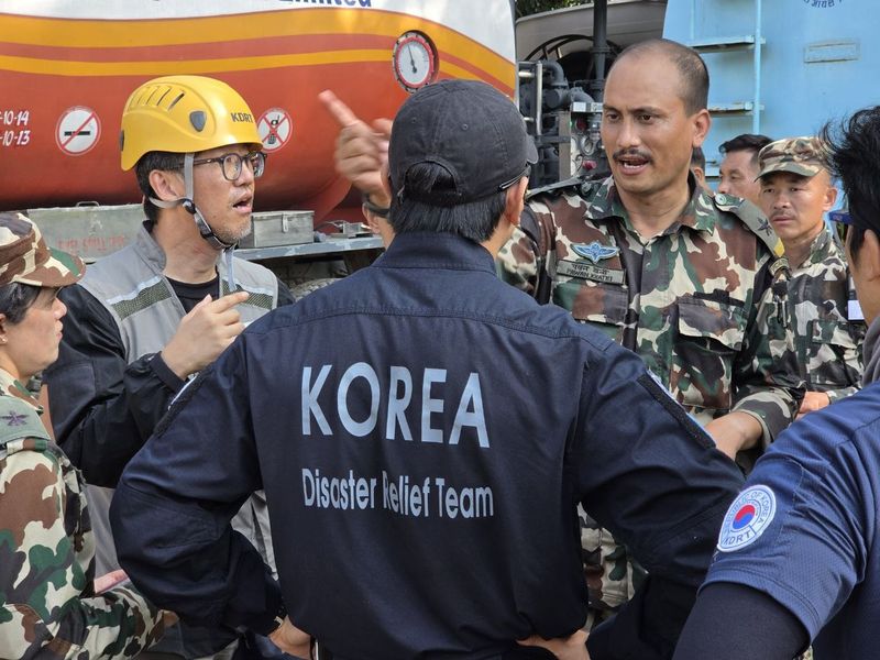 한국 해외긴급구호대(KDRT) 대원들이 8일(현지시간) 네팔 바그마티주 누와코트 바타르 네팔 군기지에서 헬기 착륙 지점을 바타르 지역 군인들과 논의하고 있다. 구호대 제공