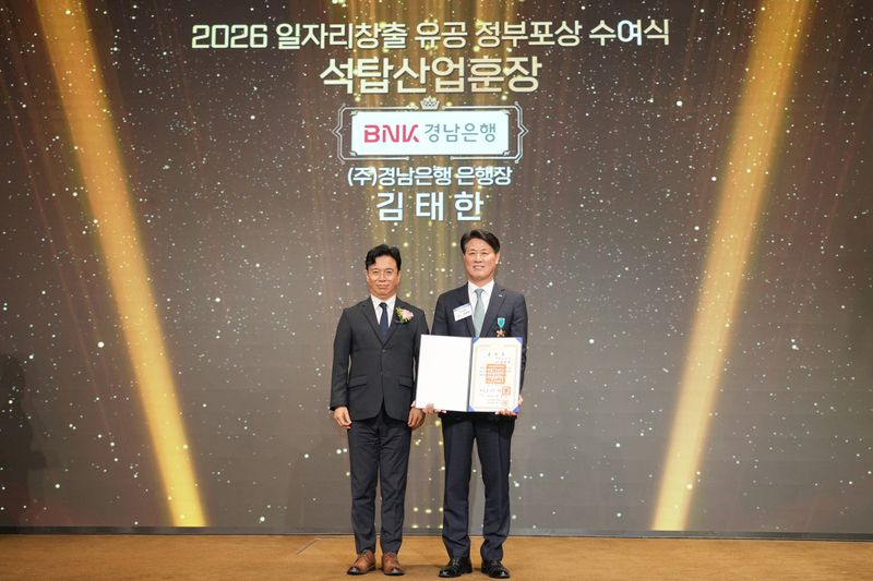 BNK경남은행 김태한 은행장(사진 오른쪽)이 고용노동부 김영훈 장관으로부터 석탑산업훈장을 받고 있다.