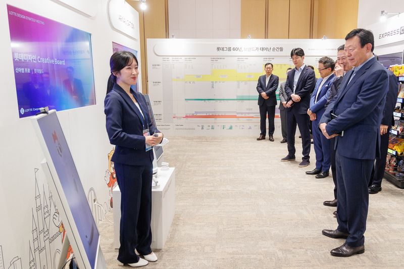10일 서울 송파구 롯데월드타워에서 열린 '2026 롯데 디자인전략회의'에서 신동빈 롯데 회장(오른쪽 첫 번째)이 젊은 디자이너들이 선보인 인공지능(AI) 프로젝트 '로티로리 로봇 롯데월드 안내 서비스'에 대해 설명을 듣고 있다. 롯데 제공