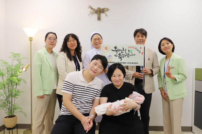 김혜원·김기민 부부가 아들을 안고 출산을 축하하기 위해 방문한 나프로임신센터 의료진과 함께 웃고 있다. 은평성모병원 제