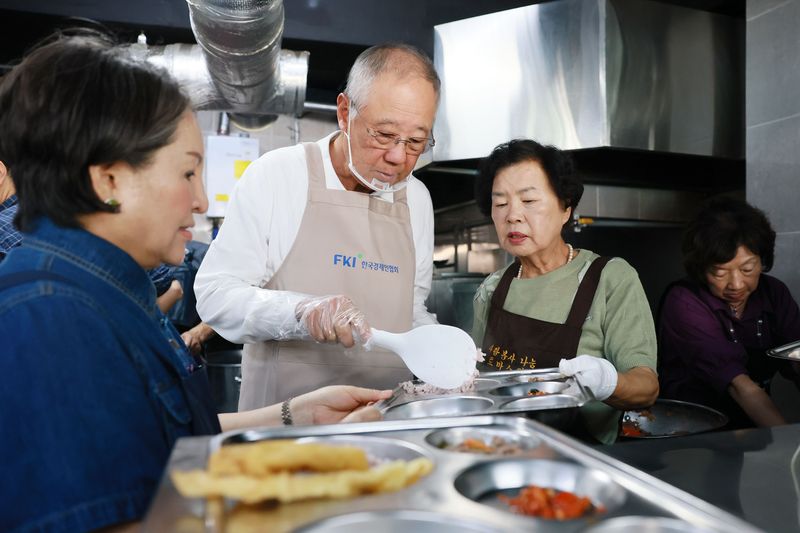 류진 한국경제인협회 회장(가운데)이 15일 서울 영등포구 무료급식소 '토마스의 집'을 찾아 배식 봉사활동을 하고 있다. 한경협 제공