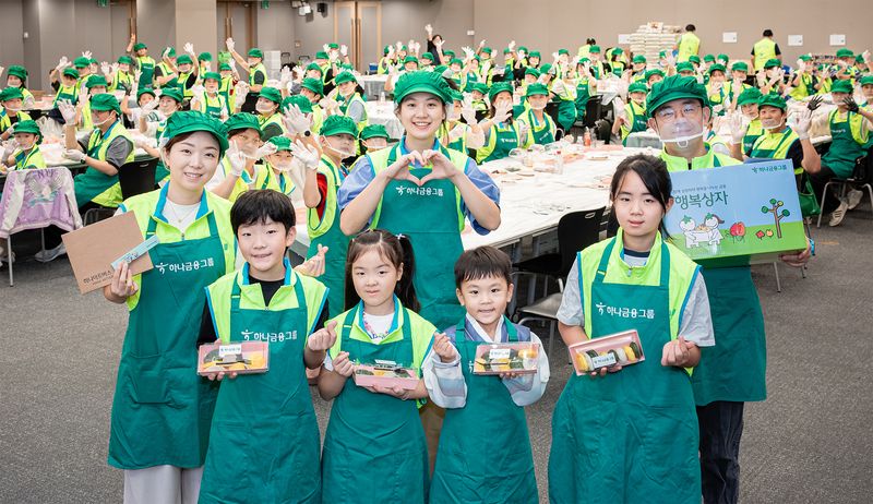 하나금융그룹은 지난 19일 서울 중구 하나금융그륩 명동 사옥에서 실시한 '사랑의 송편 빚기' 임직원 봉사활동에서 하나금융 임직원과 가족들이 직접 빚은 송편과 '한가위 행복상자'를 들고 기념촬영을 하고 있다. 하나금융그룹 제공