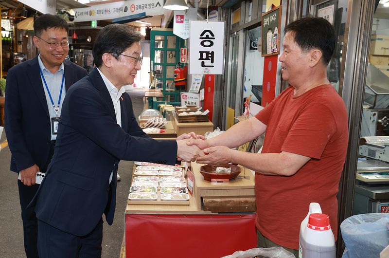 이억원 금융위원장(왼쪽)이 21일 추석을 앞두고 서울 종로구 통인시장을 찾아 상인과 이야기를 나누고 있다. 금융위원회 제공