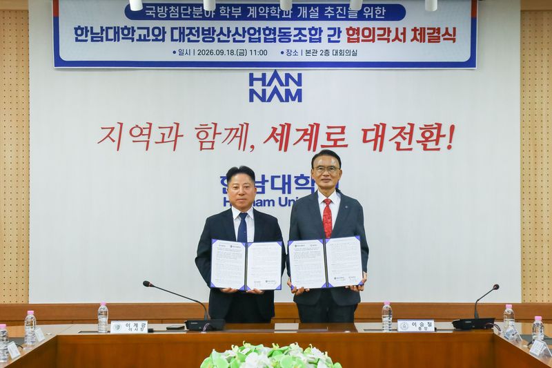 이승철 한남대 총장(오른쪽)과 이계경 대전방산사업협동조합 이사장이 지난 18일 대학본관 대회의실에서 '국방 첨단분야 학부 계약학과 개설 추진을 위한 업무협약'을 맺은 뒤 협약서를 들어 보이고 있다. 한남대 제공