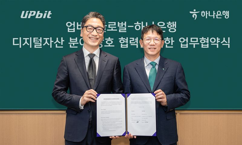 지난 15일 서울 중구 하나은행 본점에서 열린 디지털자산 분야 업무협약에 참석한 김국현 업비트 글로벌 대표(왼쪽)와 엄태성 하나은행 AI디지털혁신그룹장이 기념촬영을 하고 있다. 하나은행 제공