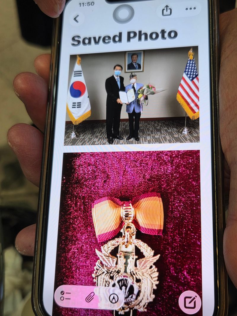하세종 참전용사가 자신의 휴대전화에 간직해온 국민훈장 수여 당시 사진을 보여주고 있다..