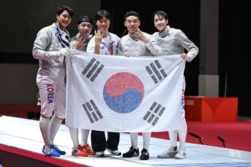 2026 아이치·나고야 아시안게임 펜싱 남자 사브르 단체전에서 4연패를 달성한 대한민국 대표팀 선수단이 국민 응원 메시지가 담긴 태극기를 들고 기념 촬영을 하고 있다. SK텔레콤 제공
