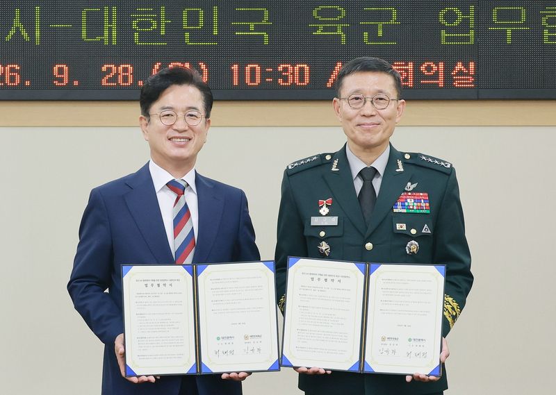허태정 대전시장(왼쪽)과 김규하 육군참모총장이 28일 대전시청에서 '방산 인공지능 전환(AX) 협력체계 구축 및 지역 방산기업 지원을 위한 업무협약'을 맺은 뒤 협약서를 들어 보이고 있다. 대전시 제공