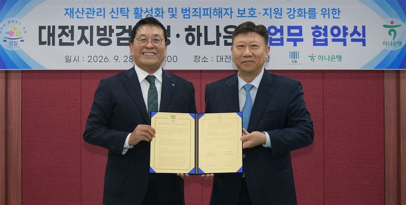 하나은행은 지난 28일 대전지방검찰청에서 대전지방검찰청과 범죄피해자를 비롯한 사회적 약자의 재산을 안전하게 보호·관리하기 위한 재산관리 신탁 활성화 업무협약을 체결하고, 협약식에 참석한 김진우 하나은행 자산관리그룹장(왼쪽)과 김도완 대전지방검찰청 검사장이 기념촬영을 하고 있다. 하나은행 제공