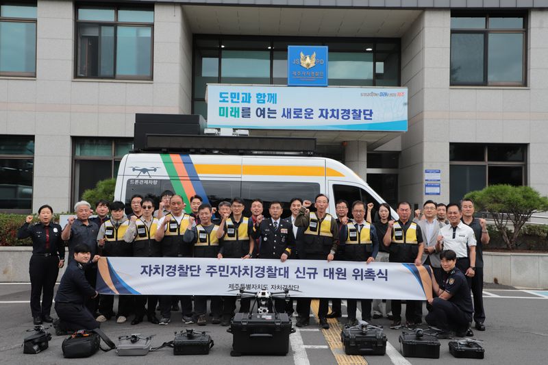 29일 제주특별자치도 자치경찰단 청사 앞에서 드론순찰 주민자치경찰대 신규 대원들이 위촉식 뒤 기념촬영하고 있다. 앞쪽에는 순찰과 수색에 활용할 드론과 장비가 놓여 있고 뒤편에는 드론관제차량이 배치돼 있다. 사진=제주특별자치도 자치경찰단