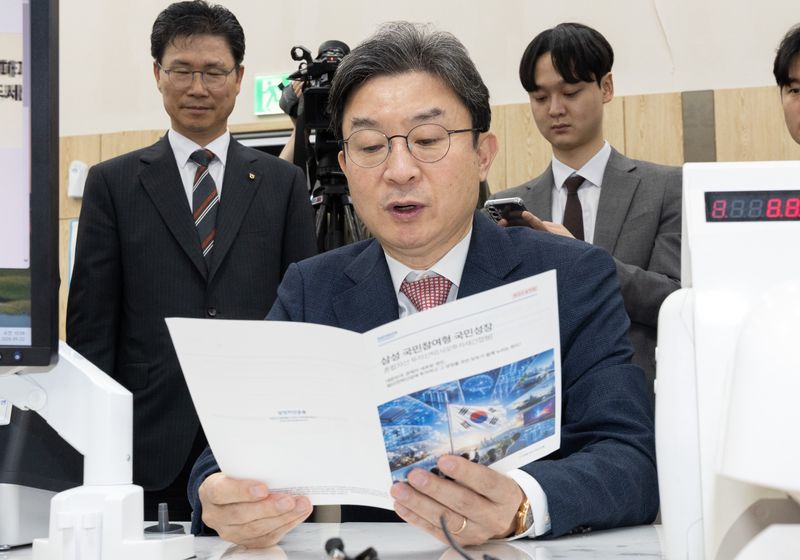 이억원 금융위원장이 5월 22일 서울 종로구 NH농협은행 정부서울청사지점에서 국민참여성장펀드 안내 책자를 살펴보고 있다. (공동취재) 2026.5.22 ⓒ 뉴스1 김성진 기자