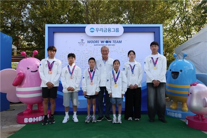 임종룡 우리금융그룹 회장(가운데)이 지난 19일 경기도 과천 서울랜드에서 열린 '2026 우리 모모콘'의 '우리드림브릿지' 선포식에 참여한 스포츠 꿈나무들과 포즈를 취하고 있다. 우리금융그룹 제공