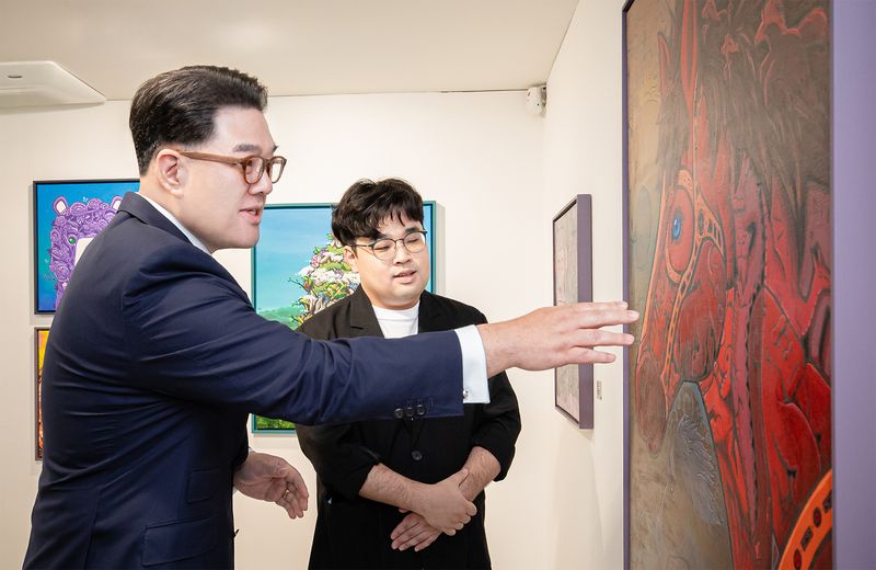 이은형 하나금융그룹 부회장(왼쪽)이 1일 서울 중구 복합문화공간 하트원에서 열린 발달장애 예술가 조태성 작가의 개인전 '하나에서 만나ZOO' 오프닝 행사에서 작가로부터 작품 설명을 듣고 있다. 하나금융그룹 제공