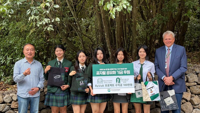 1일 제주곶자왈도립공원에서 브랭섬홀아시아와 세인트존스베리아카데미 제주 학생들이 교복 업사이클링 프로젝트 수익금 100만원을 제주곶자왈공유화재단에 전달하고 있다. 학생들은 사용하지 않는 교복과 원단을 가방으로 제작해 판매한 수익을 곶자왈 보전에 내놨다. 왼쪽은 김범훈 제주곶자왈공유화재단 이사장. 사진=제주곶자왈공유화재단