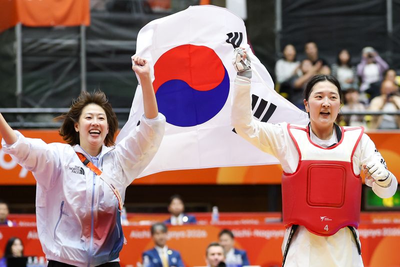대한민국 송다빈이 3일 일본 도요하시 체육관에서 열린 2026 아이치·나고야 아시안게임 태권도 여자 +67㎏급 결승전에서 중국 무원저를 꺾고 금메달을 확정 짓자 이아름 코치와 태극기를 들고 돌며 기뻐하고 있다. 2026.10.3 ⓒ 뉴스1 안은나 기자