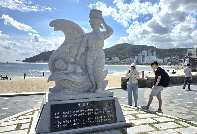 부산 송정해수욕장 동쪽 끝자락 죽도공원 입구에 있는 '섬집아기 노래비'가 해운대블루라인파크 해변열차를 이용하는 국내외 관광객들의 새로운 '관광 목록'에 올라 포토존으로 인기를 끌고 있다. 사진=변옥환 기자