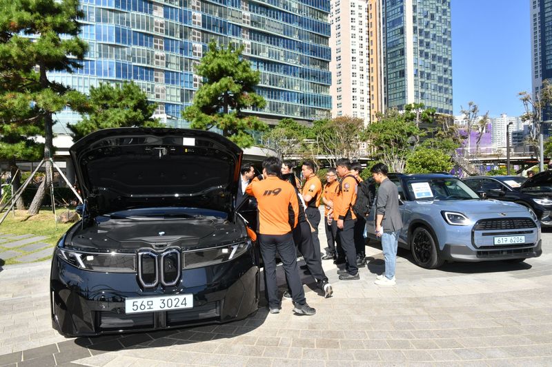 부산 해운대에서 열린 '소방대원 전기차 안전구조 세미나'에서 소방대원들이 BMW iX3(왼쪽)와 MINI 컨트리맨 전기차를 살펴보며 고전압 배터리 구조 등을 교육받고 있다. BMW 그룹 코리아 제공