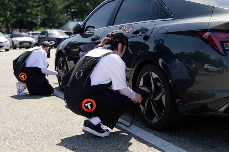 한국타이어앤테크놀로지 안전점검 캠페인에 참가한 '타이어보이'가 망상해수욕장에서 차량을 점검하고 있다. 한국타이어앤테크놀로지 제공