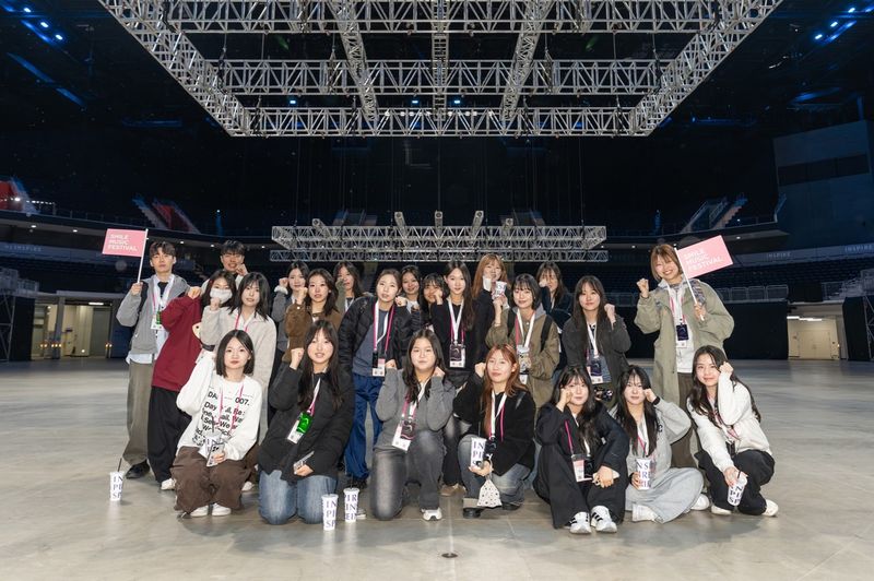 인스파이어 아레나 백스테이지 투어에 참가한 'SM 스마일 뮤직 페스티벌' 역대 수료자들이 아레나 내부에서 기념촬영을 하고 있다.