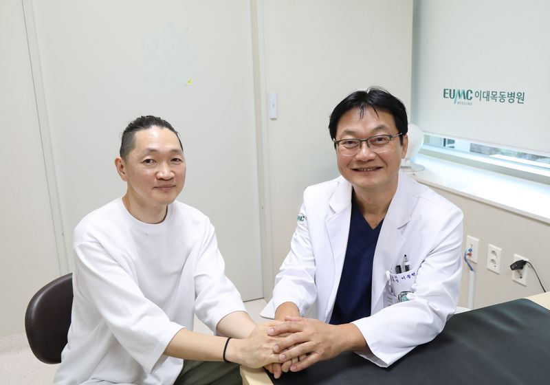 이대비뇨기병원 이동현 교수(왼쪽)가 인공방광 수술 후 약 10년간 추적관찰을 받아온 환자와 기념촬영을 하고 있다. 이대비뇨기병원 제공