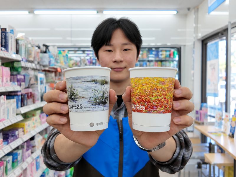 최종원 GS25 경영주가 작품을 디자인에 적용한 카페25 컵홀더를 들고 포즈를 취하고 있다. GS25 제공