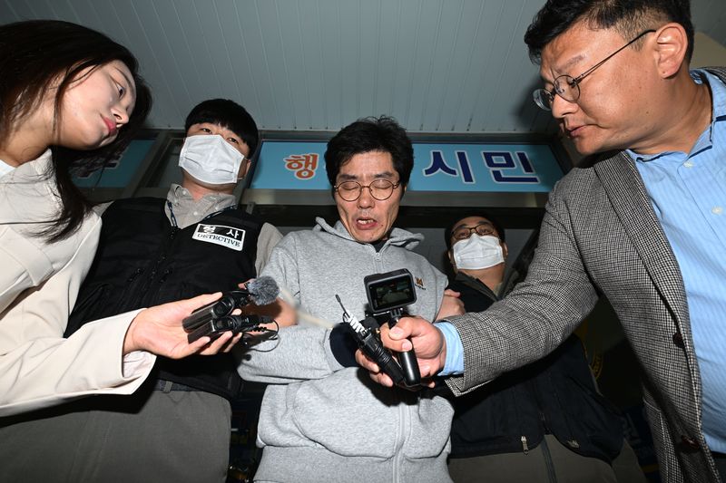 [전남광주=뉴시스] 이영주 기자 = 강도살인 혐의를 받는 박용수(53·가운데)가 16일 오전 전남광주 동구 동부경찰서에서 공소청으로 송치되고 있다. 박용수는 채무를 이유로 지인 60대 A씨 부부를 살해하고 현금카드를 빼앗아 달아난 혐의를 받고있다. 2026.10.15. leeyj2578@newsis.com
