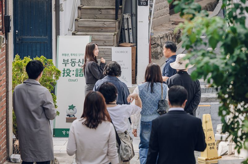 지난 20일 하나은행 '투자를 말하다, 2026 부동산 투어 세미나'에 참가한 자산가 고객들이 하나은행 부동산 전문위원의 설명을 들으며 서울 종로구 북촌 일대 골목 상권을 직접 둘러보고 있다. 하나은행 제공