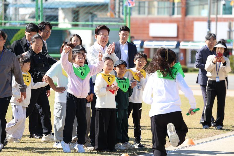 이재명 대통령이 22일 전북 익산 왕궁초등학교에서 열린 가을 행복학교 체육한마당에서 이어달리기 결승선 테이프를 잡고 학생들을 응원하고 있다. 뉴시스