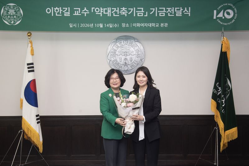 이향숙 이화여대 총장(왼쪽)이 지난 14일 서울 서대문구 교내 본관에서 열린 '약대건축기금' 전달식에서 1억 원을 기부한 이한길 약학과 교수에게 꽃다발을 전달하며 기념 촬영을 하고 있다. 이화여대 제공