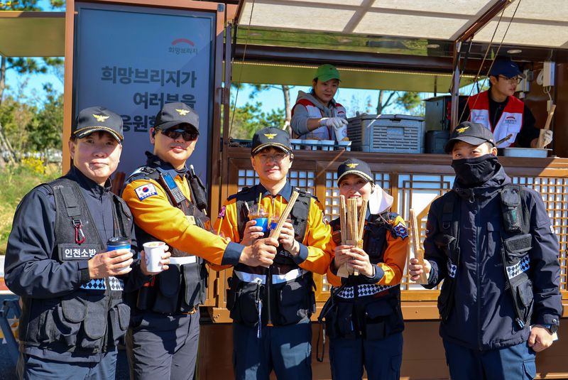 지난 22일 인천 영종도에서 열린 '국가단위 긴급구조종합훈련' 현장에서 소방대원들이 희망브리지가 지원한 간식을 들고 기념촬영하고 있다. 희망브리지 제공