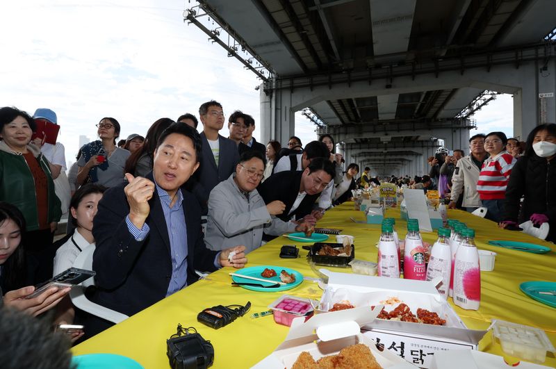 [서울=뉴시스] 김명년 기자 = 오세훈 서울시장이 25일 오후 서울 서초구 잠수교에서 열린 '잠수교 치킨데이'에서 치킨을 시식하며 관계자들과 대화하고 있다. 2026.10.25. kmn@newsis.com