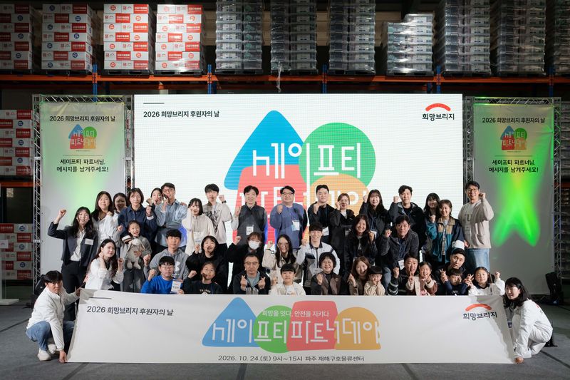 지난 24일 경기 파주 재해구호물류센터에서 열린 '2026 세이프티 파트너 데이'에 참석한 정기후원자와 가족 등이 기념촬영을 하고 있다. 희망브리지 제공