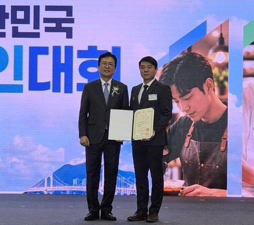[부산=뉴시스]경상남도소상공인연합회 신영철(오른쪽) 회장이 부산광역시 벡스코에서 열린 중소벤처기업부 주최 '2026년 대한민국 소상공인대회' 유공자 시상식에서 국무총리 표창을 받은 후 기념촬영하고 있다.(사진=경남소상공인연합회 제공) 2026.10.26. photo@newsis.com
