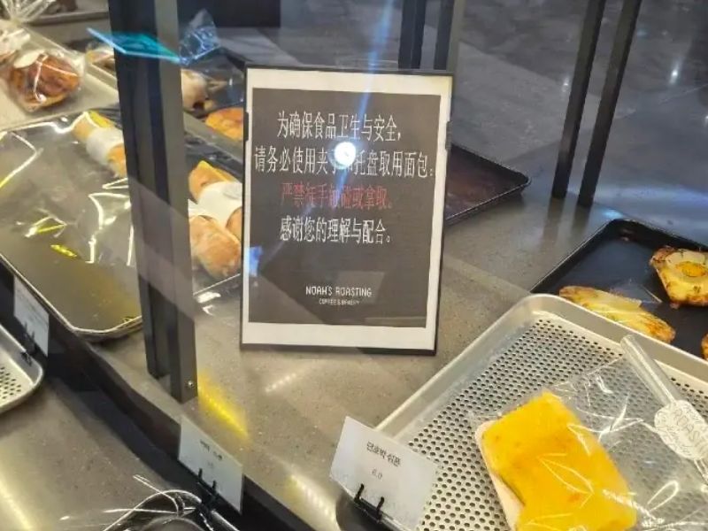 빵 진열대 사이에 맨손으로 빵을 만지거나 집는 것을 금지한다는 내용의 중국어 안내문이 세워져 있다. 빵 이름표는 한국어로 표기돼 있지만 안내문은 중국어로만 작성돼 있다. /사진=보배드림