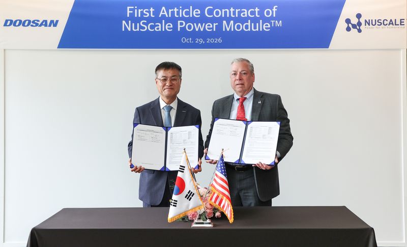 29일 창원 본사에서 열린 계약 체결식에서 뉴스케일파워 칼 피셔 COO(사진 오른쪽)와 두산에너빌리티 김종두 사장이 기념 촬영하고 있다. 두산에너빌리티 제공